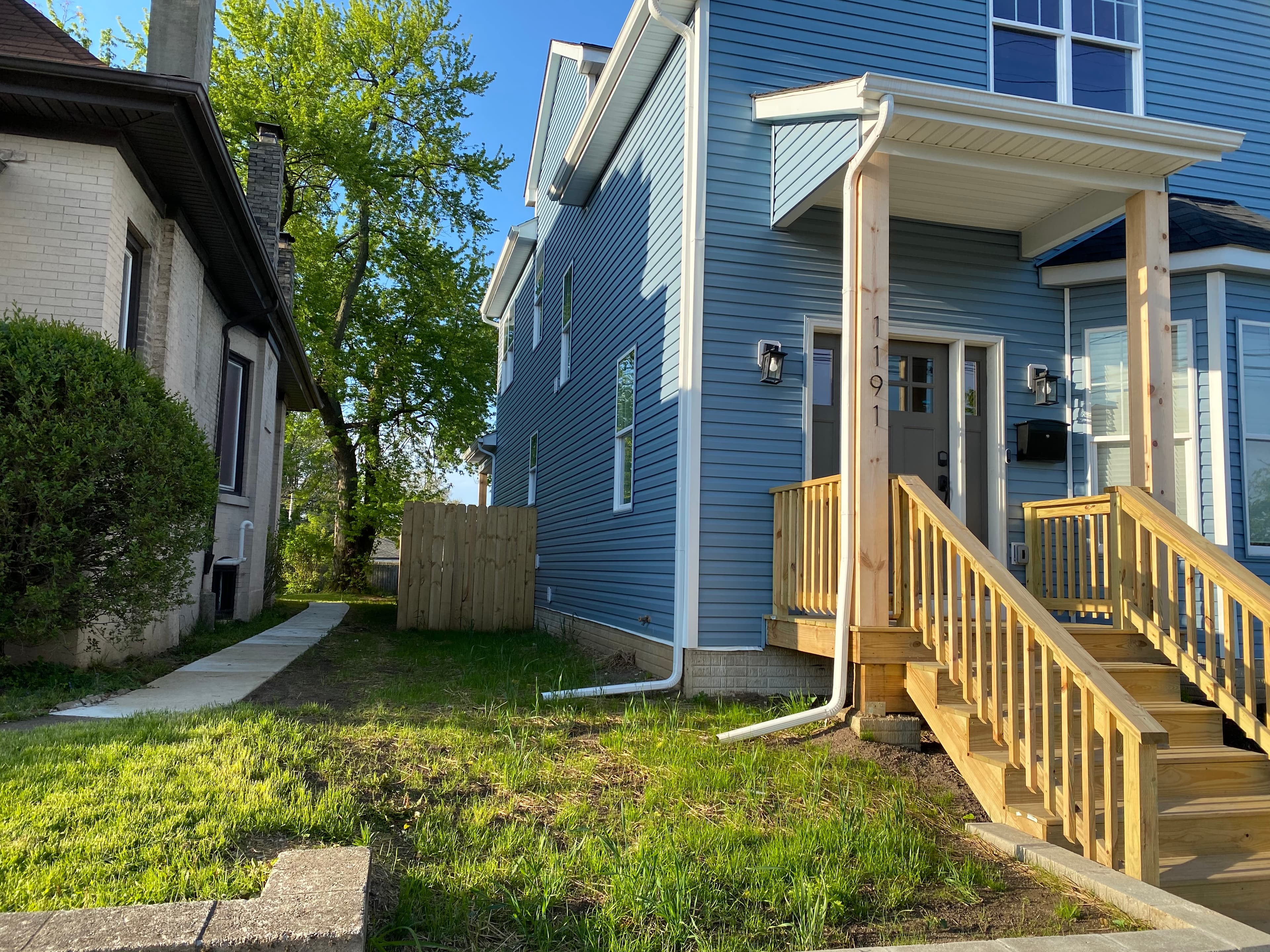 Blue-sided home with white trim and a wooden front porch and steps